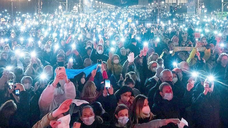 Zahlreiche Zuschauer leuchten mit ihren Handy-Taschenlampen bei „Sound of Peace“ am Brandenburger Tor. Foto: Christophe Gateau/dpa