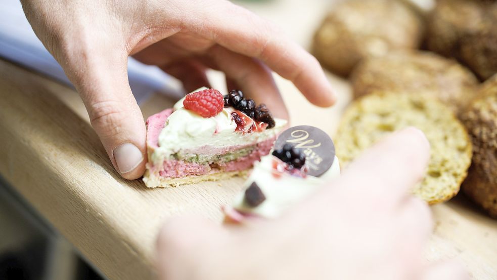 Ein Bäckermeister zeigt ein aufgeschnittenes Tartelette. Foto: DPA
