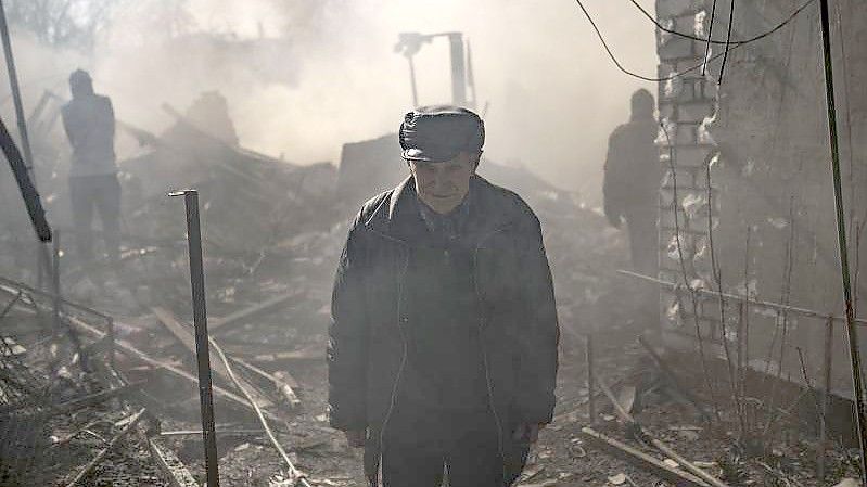 Ein Mann steht inmitten des Rauchs eines brennenden Hauses, das nach einem russischen Angriff in Charkiw zerstört wurde. Foto: Felipe Dana/AP/dpa