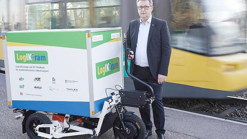 Michael Frey, stellvertretender Leiter des Instituts für Fahrzeugsystemtechnik am Karlsruher Institut für Technologie (KIT), mit dem Prototyp eines Ladungsträgers an einer Straßenbahnhaltestelle. Foto: Uwe Anspach/dpa