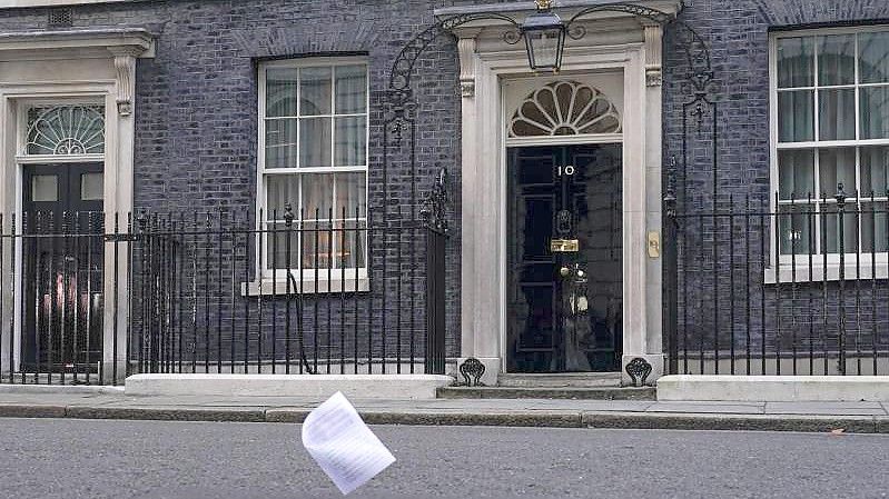 Eine Kopie des Berichts zu den mutmaßlichen Lockdown-Verstößen im britischen Regierungssitz fliegt an der Eingangstür der 10 Downing Street vorbei. Foto: Alberto Pezzali/AP/dpa