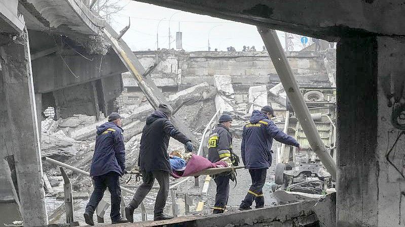 Ukrainische Rettungskräfte tragen eine ältere Frau durch den befreiten Kiewer Vorort Irpin. Foto: Efrem Lukatsky/AP/dpa