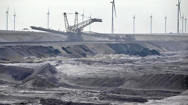 Bergbaumaschinen arbeiten im Braunkohletagebau Garzweiler, im Hintergrund Windräder. Foto: Federico Gambarini/dpa