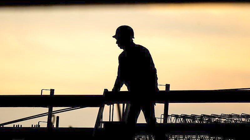 Die Silhouette eines Bauarbeiters am Morgen: Im Konflikt um den tariflichen Mindestlohn in der Bauwirtschaft haben die Arbeitgeber den Schlichterspruch abgelehnt. Foto: Julian Stratenschulte/dpa