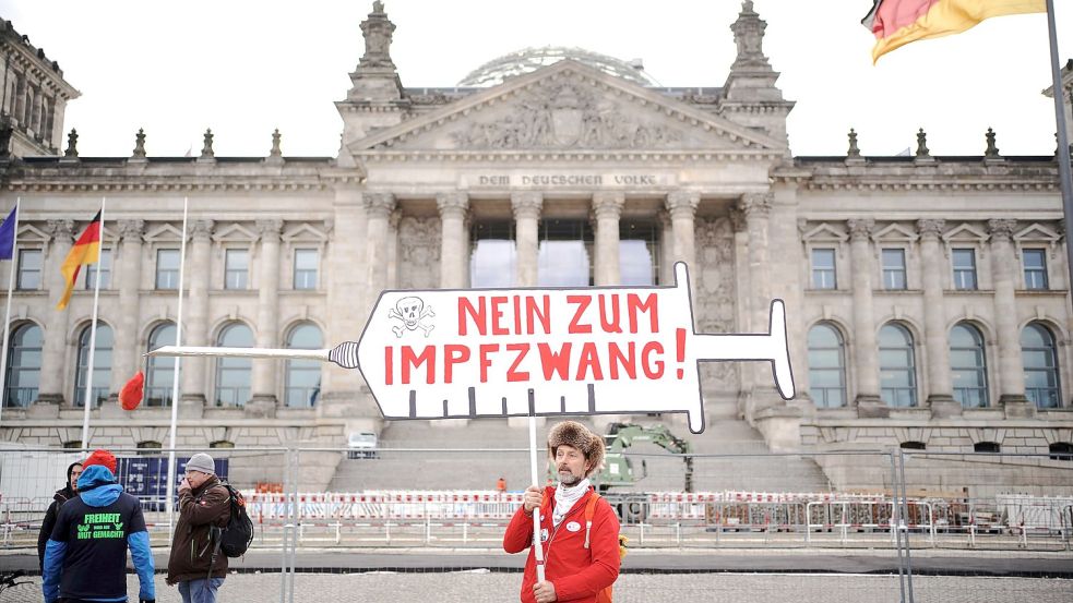 Ein Demonstrant steht am Donnerstagmorgen mit einem Plakat mit der Aufschrift „Nein zum Impfzwang!“ vor dem Reichstagsgebäude in Berlin. Foto: DPA