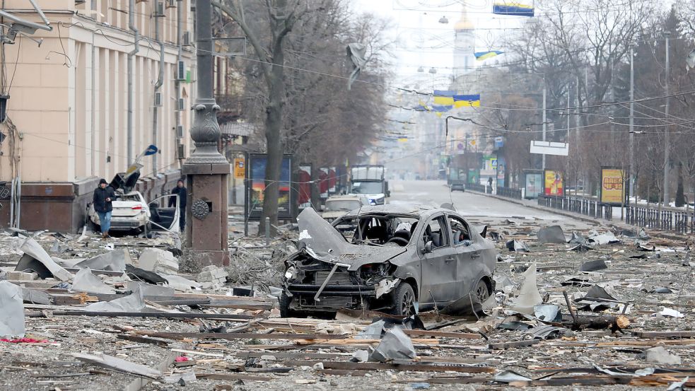 Ein ausgebranntes Autos steht auf der Straße in der Nähe des durch Angriffe zerstörten Gebäudes der regionalen Verwaltung von Charkiw auf dem Freiheits-Platz, dem Svobody-Platz. Foto: DPA