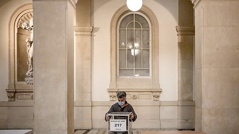 Ein Angestellter des Rathauses bereitet ein Wahllokal in Lyon vor. Die Präsidentschaftswahlen werden voraussichtlich in zwei Runden am 10. und 24. April 2022 stattfinden. Foto: Jeff Pachoud/AFP/dpa