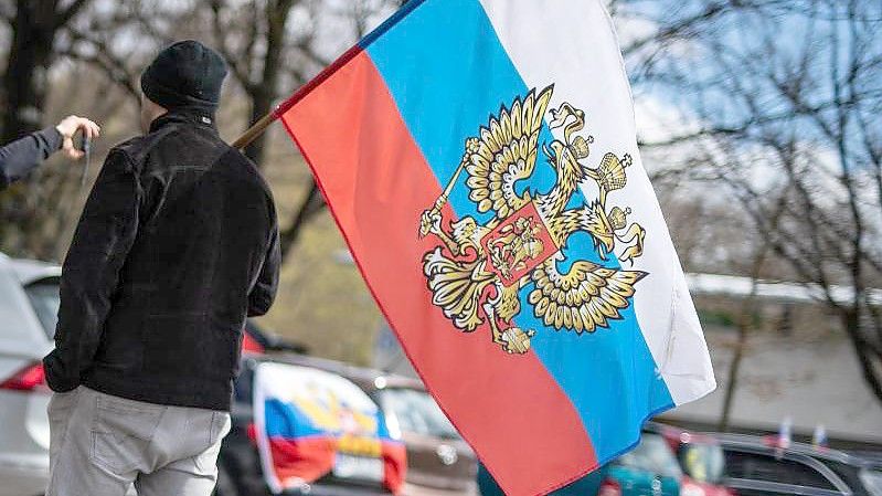 Ein Teilnehmer mit einer russischen Russische Flagge. Foto: Christoph Schmidt/dpa/Archiv