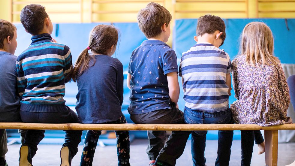 Kinder sitzen auf einer Bank. Foto: DPA