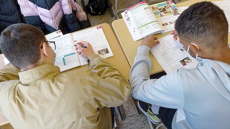 Ein aus der Ukraine geflohne Schüler (l) arbeitet in einer Deutsch-Fördergruppe. Foto: Henning Kaiser/dpa