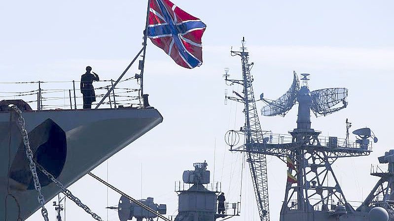 Ein russischer Matrose (l) salutiert am Bug des Raketenkreuzers „Moskwa“. Foto: Pavel Golovkin/AP/dpa