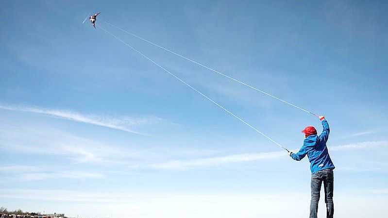 Ein Junge lässt bei schönem Wetter seinen Flugdrachen am Nordseestrand von Cuxhaven fliegen. Foto: Mohssen Assanimoghaddam/dpa