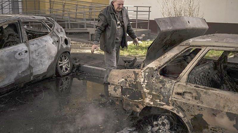 Ein Mann begutachtet sein verbranntes Auto nach einem russischen Angriff in Charkiw. Foto: Felipe Dana/AP/dpa