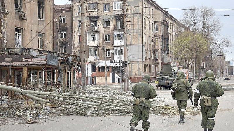 Soldaten der Miliz der „Volksrepublik“ Donezk gehen an beschädigten Wohnhäusern in Mariupol vorbei. Foto: Alexei Alexandrov/AP/dpa