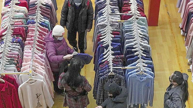 Menschen beim Kleiderkauf in einem Einkaufszentrum in Peking. Foto: Andy Wong/AP/dpa