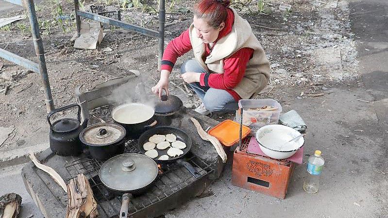 Eine Frau in Mariupol kocht am Straßenrand Essen. Die Hafenstadt ist seit dem 1. März vollständig von russischen Truppen eingeschlossen. Foto: Victor/Xinhua/dpa