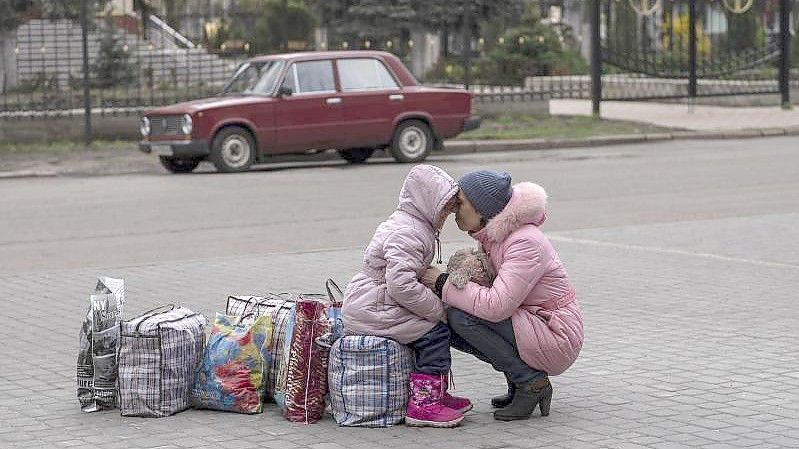Eine Mutter wartet mit ihrer Tochter auf einen Bus, um aus der Stadt Slowjansk zu fliehen. Foto: Petros Giannakouris/AP/dpa