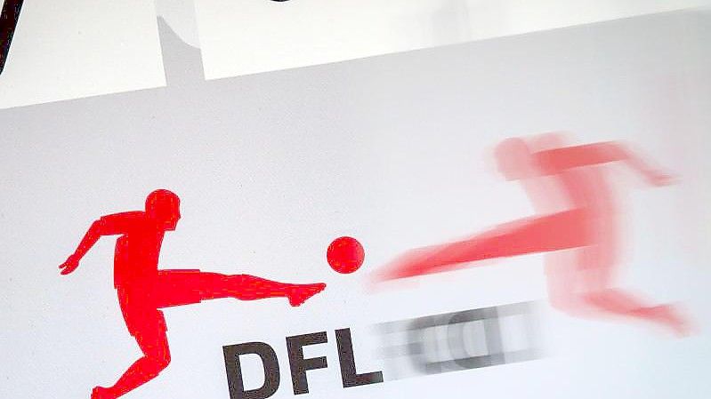 Das Logo der Deutschen Fußball Liga (DFL) spiegelt sich vor Beginn einer Pressekonferenz in einer transparenten Trennscheibe. Foto: Frank Rumpenhorst/dpa
