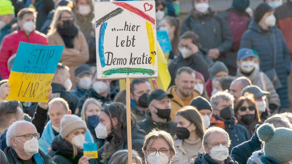 Ein Teilnehmer hält ein Plakat mit der Aufschrift "...hier lebt Demokratie" bei einer Demonstration. Foto: DPA