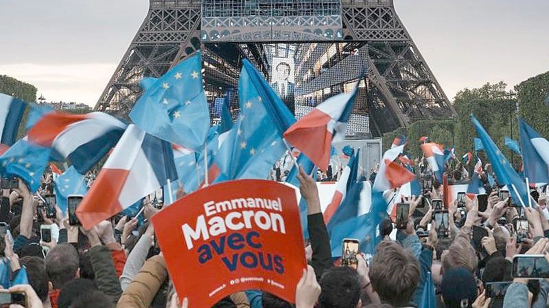 Anhänger des französischen Präsidenten Macron reagieren am Eiffelturm auf die Bekanntgabe der ersten Wahlprognosen. Foto: Thibault Camus/AP/dpa