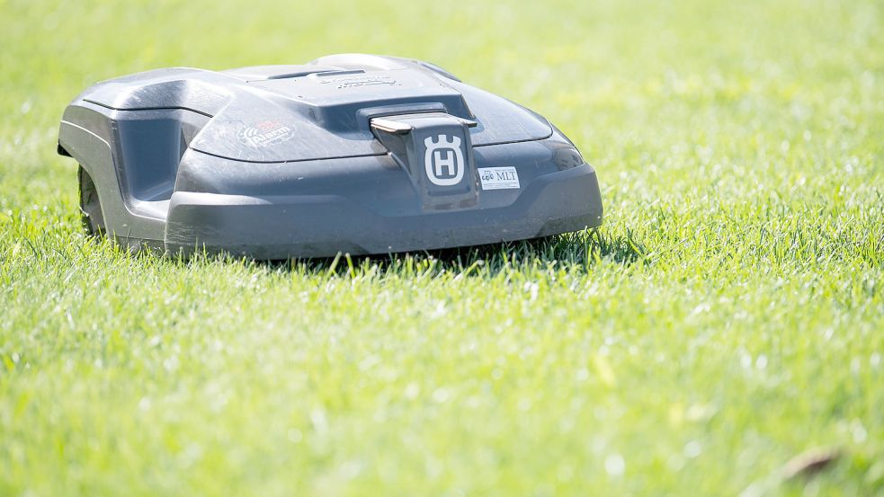 Ein Rasenmähroboter fährt über eine Wiese. Foto: DPA