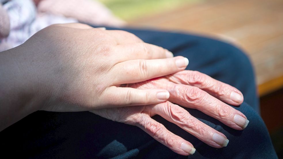 Eine junge Frau berührt die Hand einer Seniorin. Foto: picture alliance/dpa/Sina Schuldt