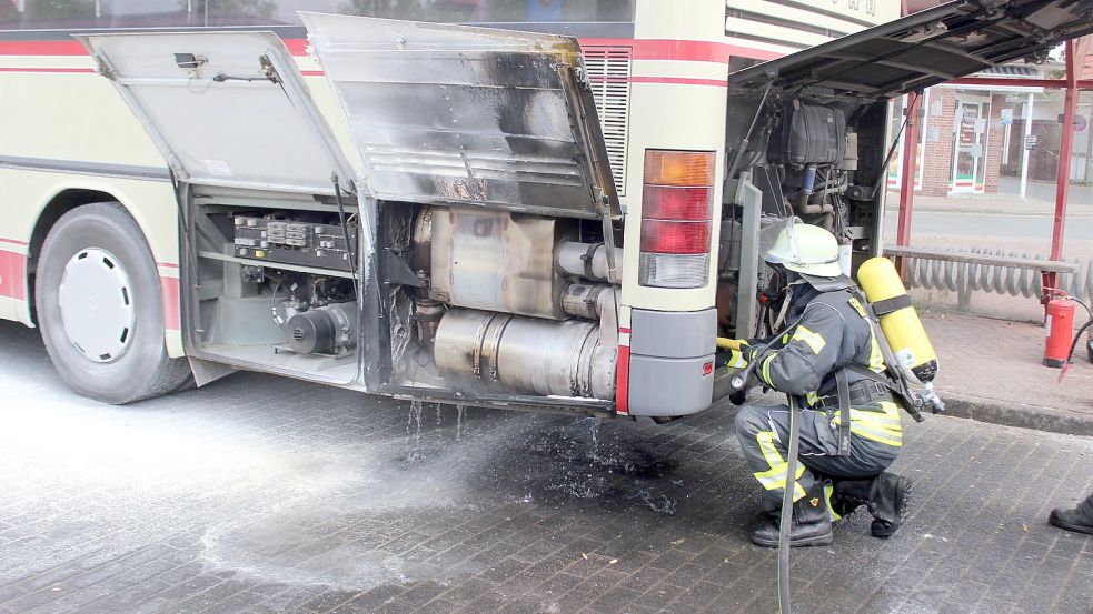 Nach dem Löschen des Feuers kühlt ein Feuerwehrmann den Motor eines Busses in Wiesmoor, Foto: Jan-Marco Bienhoff