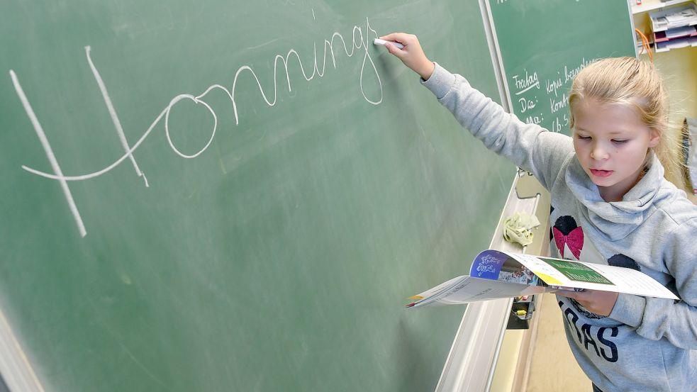 Eine Schülerin in Brandenburg schreibt das niederdeutsche Wort „Honningsööt“ an die Tafel. Foto: DPA