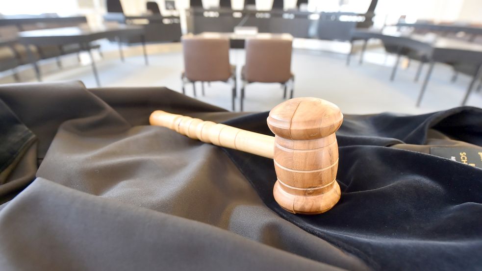 Auf einem Tisch in einem Schwurgerichtssaal liegt ein Richterhammer aus Holz, darunter liegt eine Richterrobe. Foto: DPA