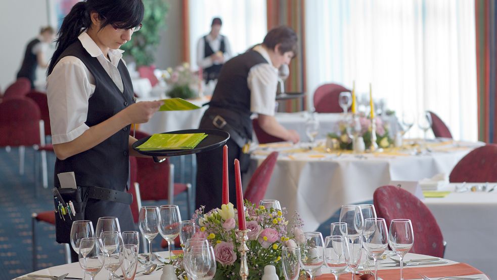 Eine Auszubildende prüft die Servietten beim Eindecken einer Festtafel. Immer weniger Menschen in Ostfriesland entscheiden sich für eine Ausbildung in der Gastronomie. Foto: DPA