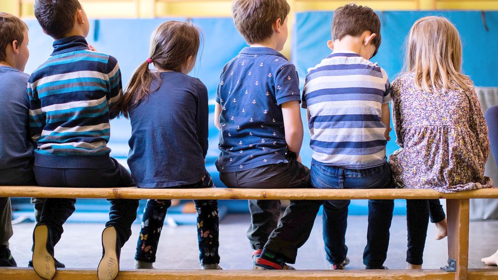 Kinder sitzen auf einer Bank. Foto: DPA