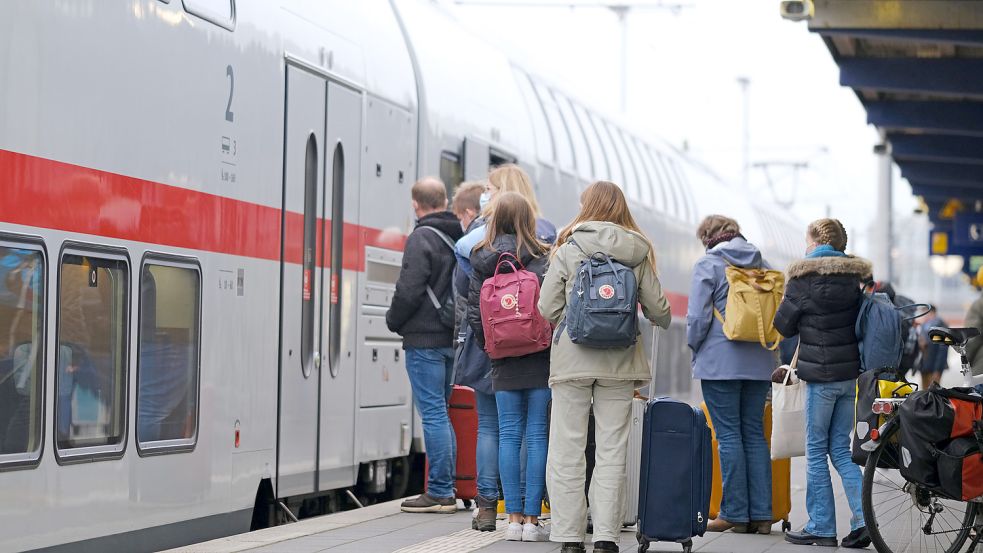 Menschen stehen an einem Sonnabend auf einem Bahnsteig am Bahnhof Norddeich Mole vor einem Zug. Foto: DPA