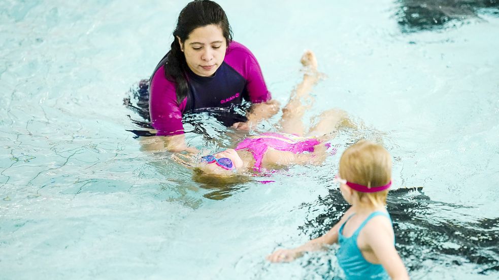 Eine Kursleiterin bringt den jungen Teilnehmern das Schwimmen bei. Foto: DPA