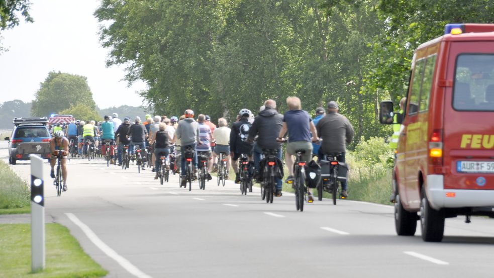 Hier wird es eng: Ein Auto mit Anhänger überholt den Korso auf der K111. Doch von vorne kommt ihm ein Rennradler entgegen, der sich am Auto vorbeischieben muss. Foto: Kim Hüsing