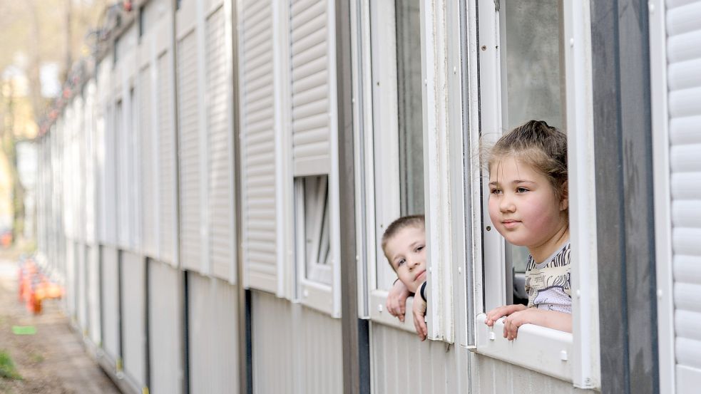 Ukrainische Kinder schauen aus den Fenstern einer Siedlung für Geflüchtete. Auch im Landkreis Aurich sollen nun vermehrt Wohncontainer zum Einsatz kommen. Foto: DPA