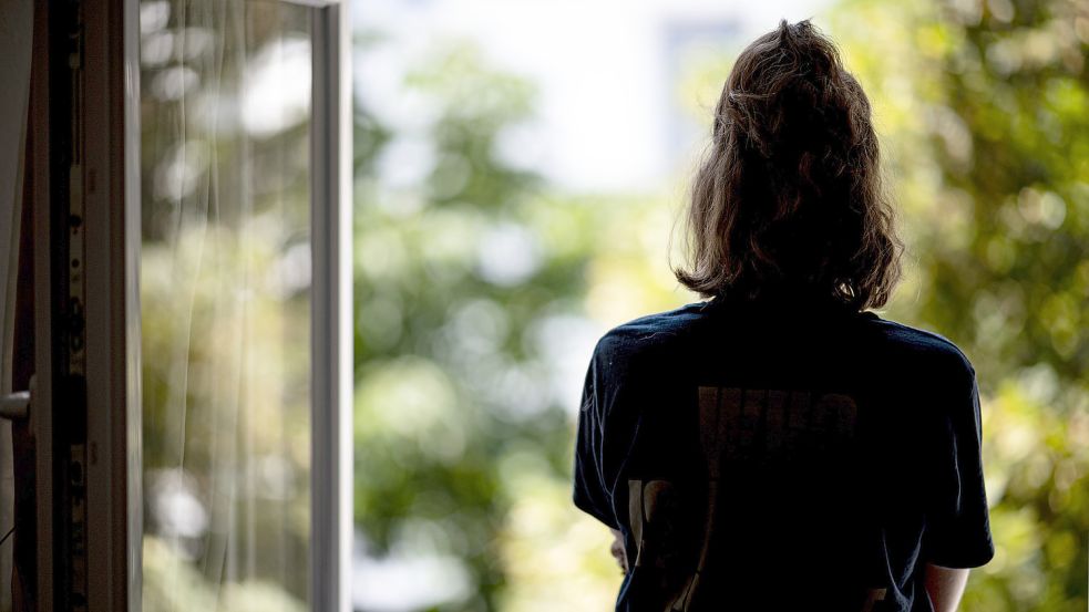 Eine Frau steht in ihrer Wohnung an einem Fenster. Foto: DPA