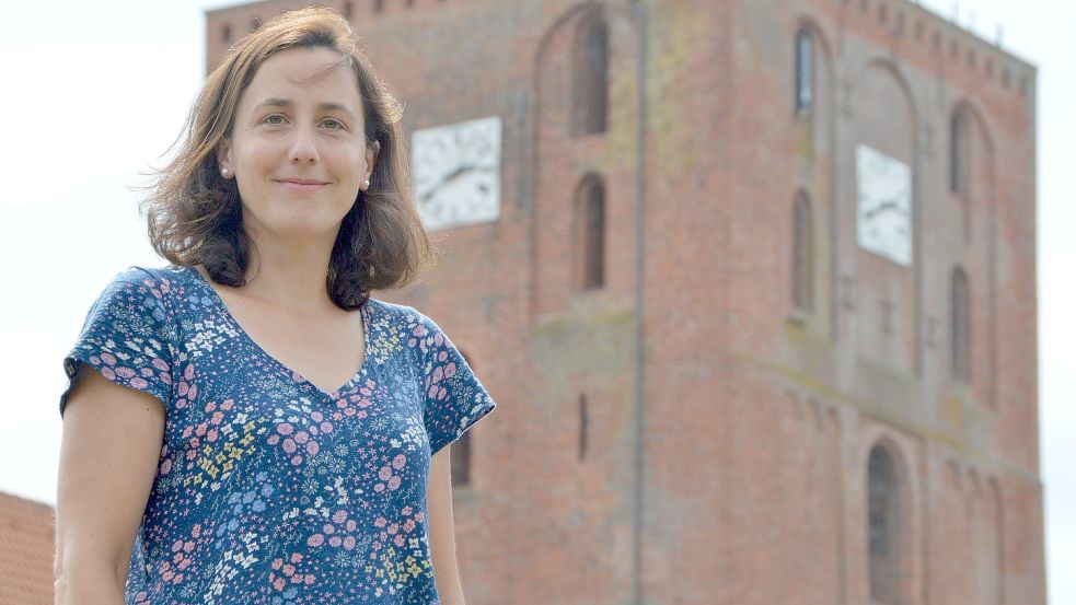 Pastorin Katrin Krüger vor ihrem bisherigen Arbeitsplatz, der Marienhafer Marienkirche. Das Gotteshaus und seine Lage findet sie „traumhaft“. Foto: Thomas Dirks