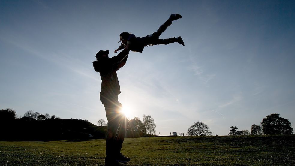 Ein Vater wirbelt sein Kind in die Luft. Foto: DPA
