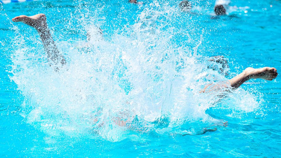 Ein Junge springt kopfüber in ein Schwimmbecken. Foto: DPA