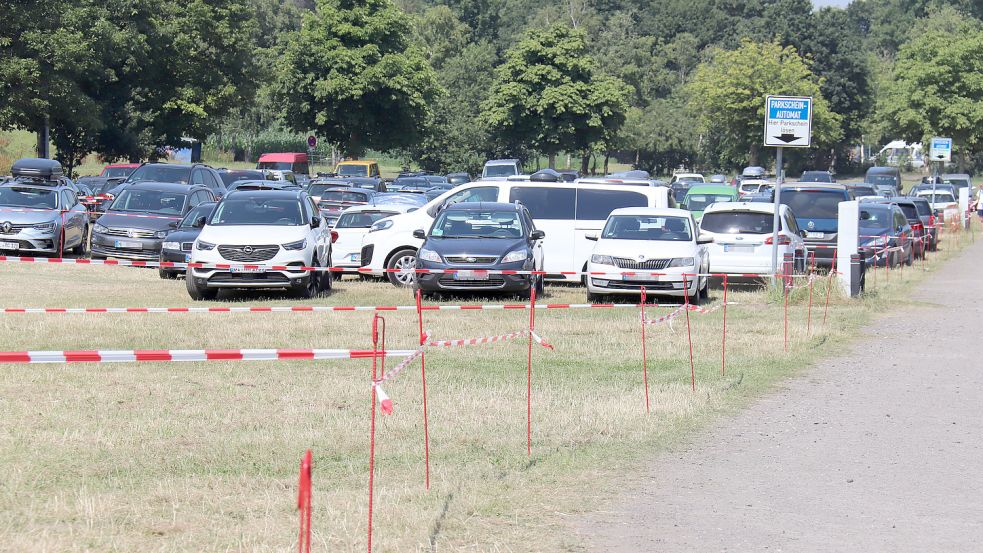 Mit Flatterband ist am Mittwochmorgen die Wiese in Stellplätze eingeteilt worden, die am Tannenhausener Badesee als Parkplatz dient. Foto: Heino Hermanns