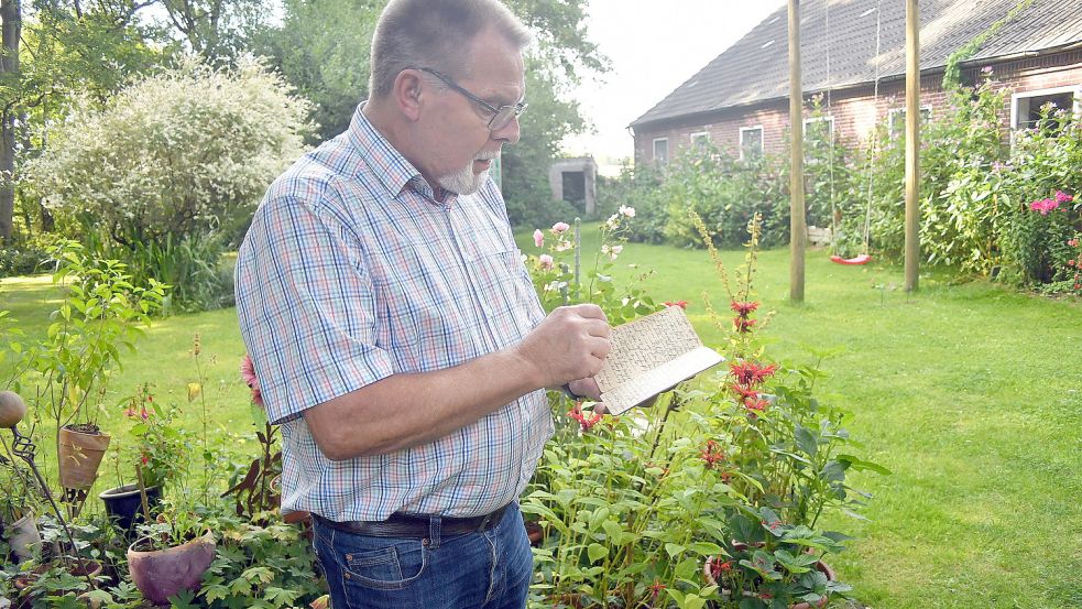 Volkmar Ehmen sieht sich in seinem Garten das Taschenbuch seines Großonkels Metzen Ehmen an. Fotos: Gerd-Arnold Ubben