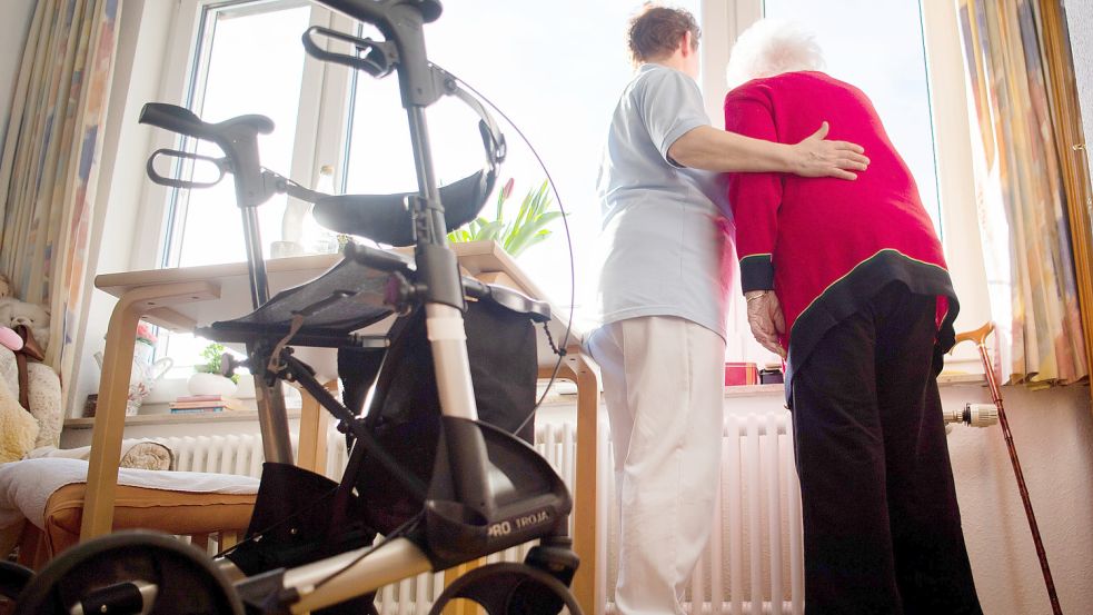 Eine Pflegerin (links) und eine Bewohnerin eines Pflegeheims schauen zusammen aus einem Fenster. Foto: DPA