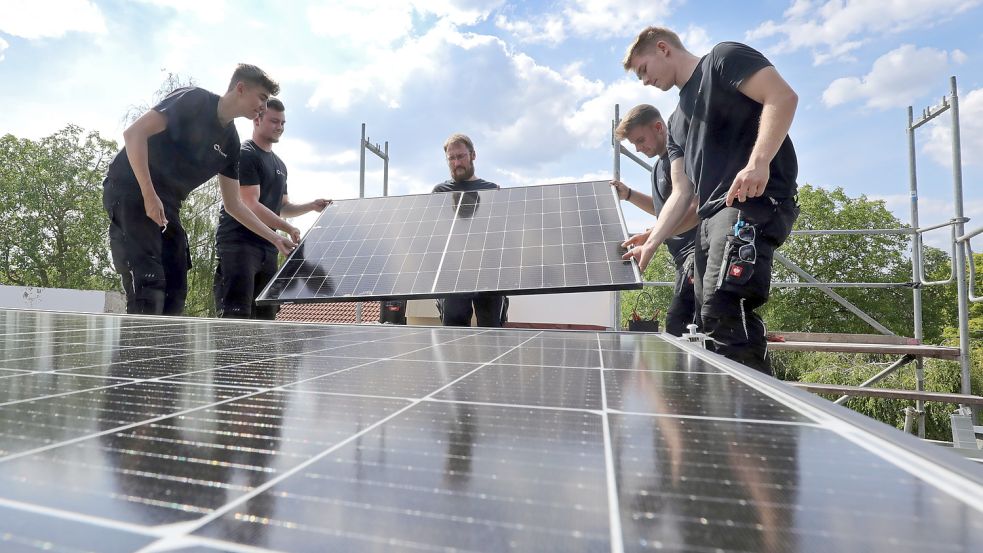 Handwerker montieren Solarmodule auf einem Dach.Foto: DPA