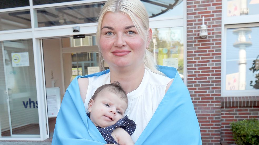 Maria Al-Battat hält ihre Tochter Adelina. Um ihre Schultern ist eine ukrainische Flagge gelegt. Foto: Romuald Banik