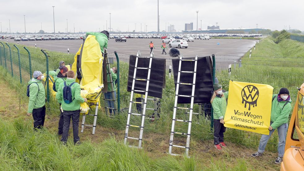 Mit Leitern kletterten die Greenpeace-Mitglieder über den Zaun zu den riesigen VW-Stellflächen im Emder Außenhafen. Foto: DPA