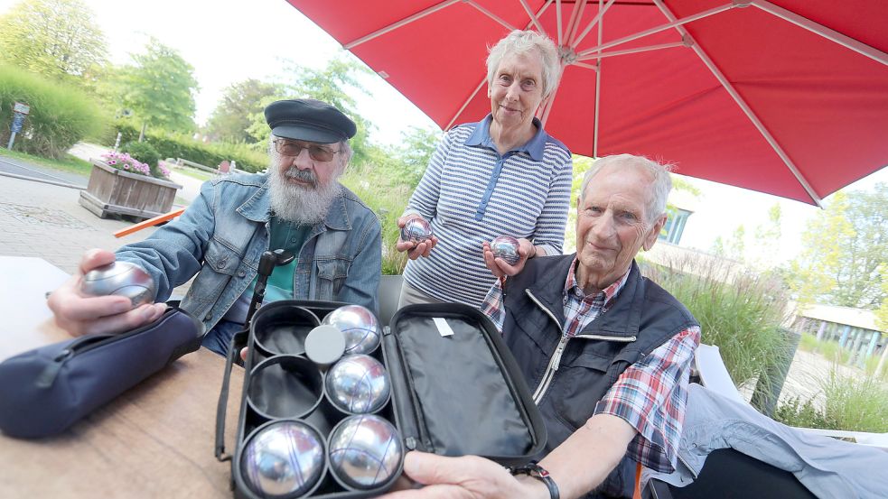 Franz Galliat (89 Jahre, von links), und das Ehepaar Else (85) und Johann (87) Gellmers aus Kirchdorf lassen ihre Boulekugeln auf der Bahn am Auricher Familienzentrum rollen. Galliat ist der Novize der Seniorencrew. Er nahm im Frühjahr erstmals die Kugeln in die Hand. Das Gellmers-Duo gehört seit 2019 der Boulegruppe an. Gespielt wird immer montags das ganze Jahr über. Fotos: Romuald Banik