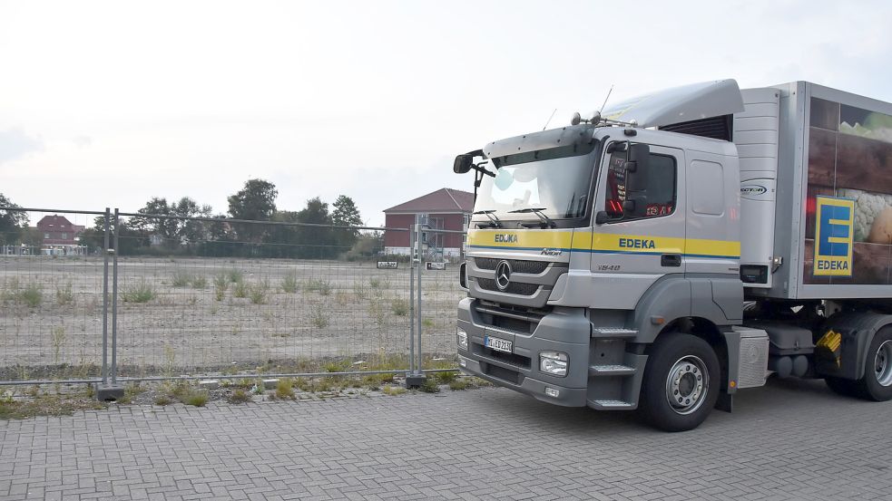 Ein Lastwagen der Edeka parkt an der Fläche nahe der IGS (im Hintergrund) in der Marienhafer Rosenstraße, auf der bis 2023 das neue E-Center entstehen soll, seit einiger Zeit aber kein Fortschritt zu erkennen ist. Foto: Thomas Dirks