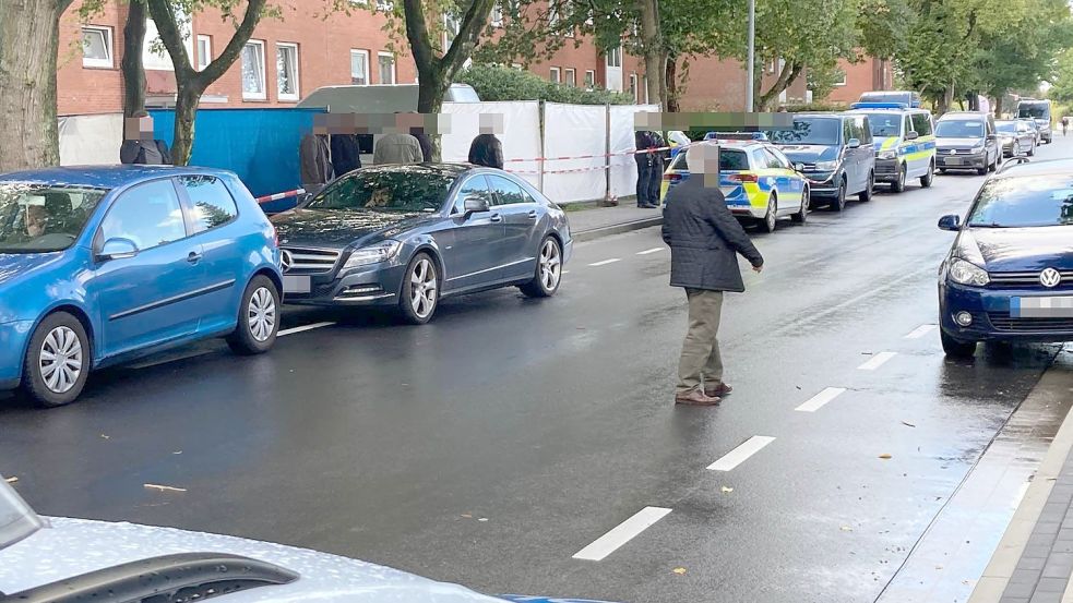 Mehrere Beamte sperren den Eingang zu einem Mehrfamilienhaus ab. Der Zugangsbereich ist mit Planen abgeschirmt. Foto: Heino Hermanns