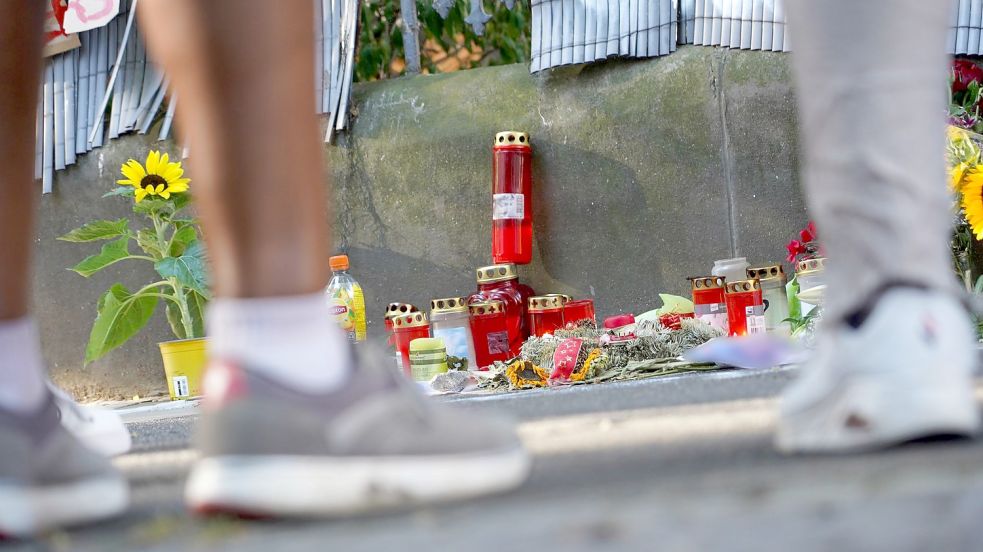 Menschen stehen vor einem Zaun, an dem mit Kerzen und Blumen eines von der Polizei erschossenen Jugendlichen gedacht wird. Foto: Gregor Bauernfeind/dpa