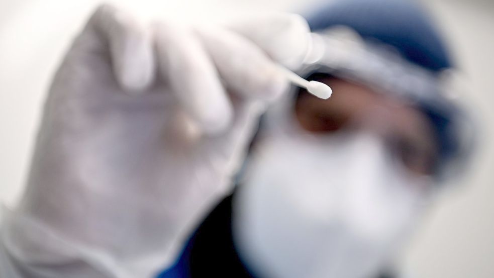 Ein Arzt samt Teststäbchen für die Entnahme einer Probe für einen PCR-Test. Foto: Britta Pedersen/dpa-Zentralbild/dpa